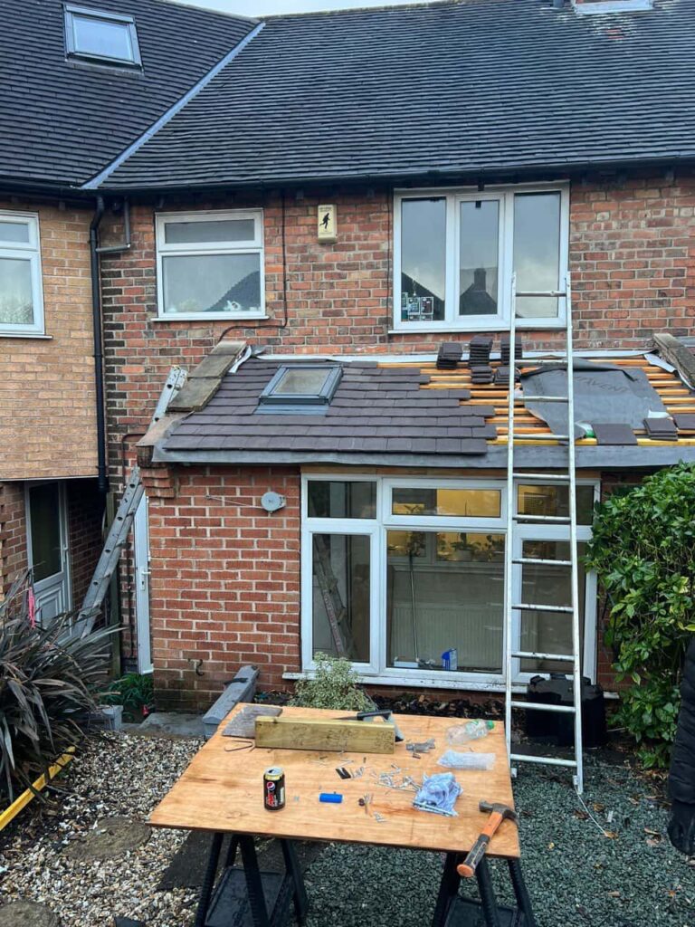 This is a photo of a roof extension that is having new roof tiles installed. This is a photo taken from the roof ridge looking down a tiled pitched roof on to a flat roof. Works carried out by Midhurst Roofing Repairs